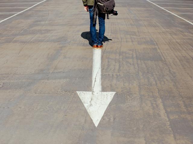 man standing in the road in front of a large arrow